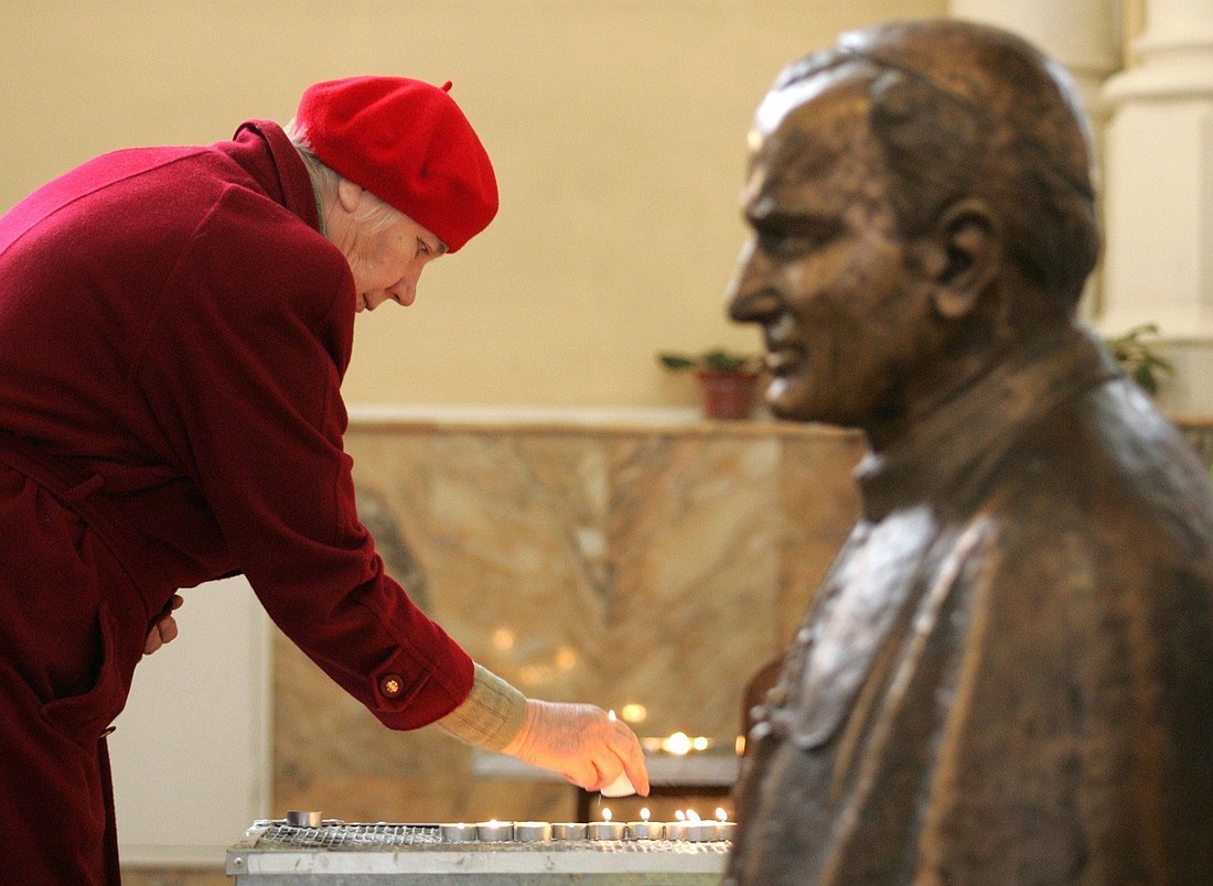 A woman is pictured in a file photo placing a lit candle next to a bust of St. Pope John Paul II at the Church of the Immaculate Conception in Moscow. The U.S. Commission on International Religious Freedom in new report says Russia is intensifying enforcement of laws targeting perceived offensive expression toward religion, religious texts and religious leaders. Prosecuting "perceived offensive expressions" about religion violates the right to freedom of religion or belief, USCIRF says. (OSV News photo/Alexander Natruskin, Reuters)