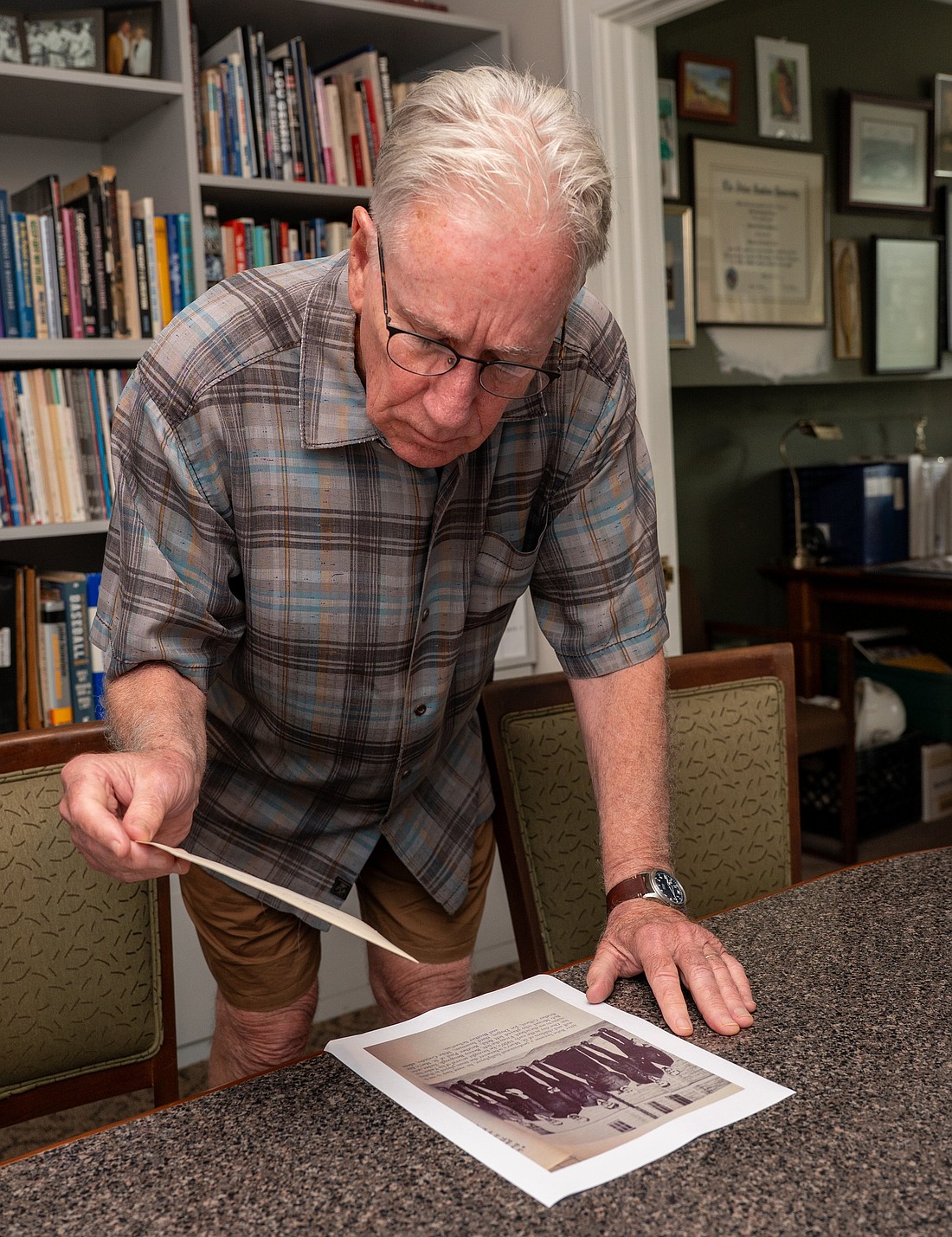 Mike Gibbons, director emeritus and historian of the Babe Ruth Birthplace and Museum in Baltimore, is seen May 6, 2025, comparing a photograph of George Herman "Babe" Ruth taken during a visit to St. Mary's Industrial School in Southwest Baltimore with another version of the same image featured in a book about the legendary player. The small print he is holding was sent to Archbishop William E. Lori for the Baltimore archdiocesan archives by Ginny Black of Mount Pleasant, S.C., who found it while searching through her late mother’s possessions. (OSV News photo/Kevin J. Parks, Catholic Review)
