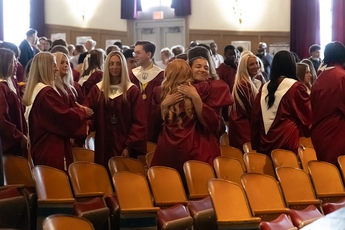 At the Sign of Peace, two Holy Cross Preparatory Academy, Delran, graduates exchange a hug during the May 30 Baccalaureate Mass celebrated by Father James Grogan, pastor of Our Lady of Good Counsel Parish, Moorestown. Jan Griswold photo