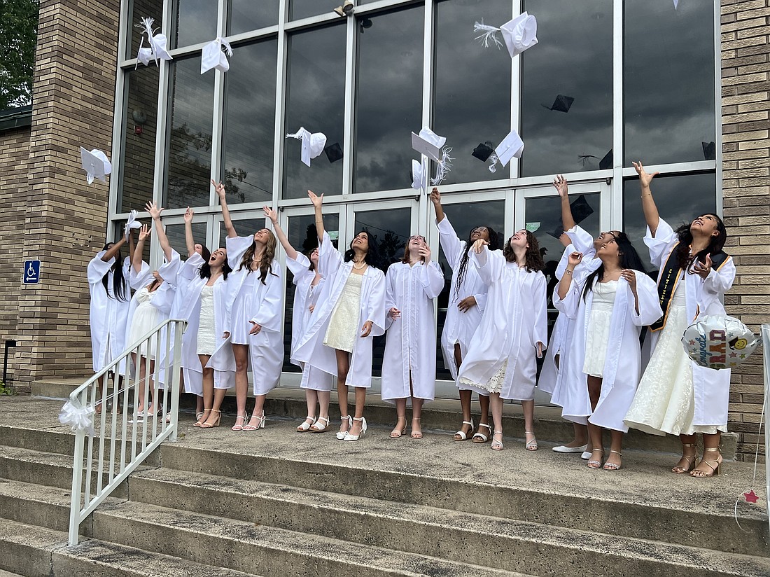On the front steps to their school building happy graduates toss their mortarboards in the air. Elizabeth Zimak photo