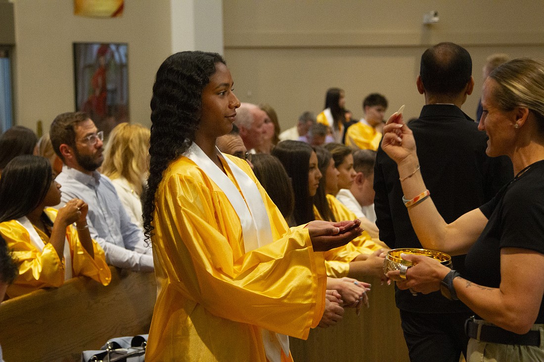 Graduate Aleena Dinker receives the Eucharist from Staci Shalkowski, a school guidance counselor during the Baccalaureate Mass. Ryan Larason photo