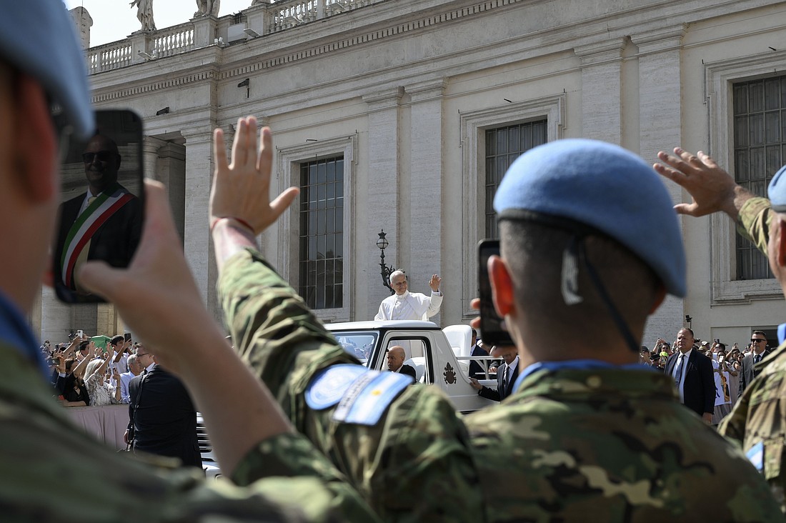 Pope Leo XIV waves to a delegation of UN peacekeepers a child as he arrives in St. Peter's Square on the popemobile for his general audience June 18, 2025. (CNS photo/Vatican Media)