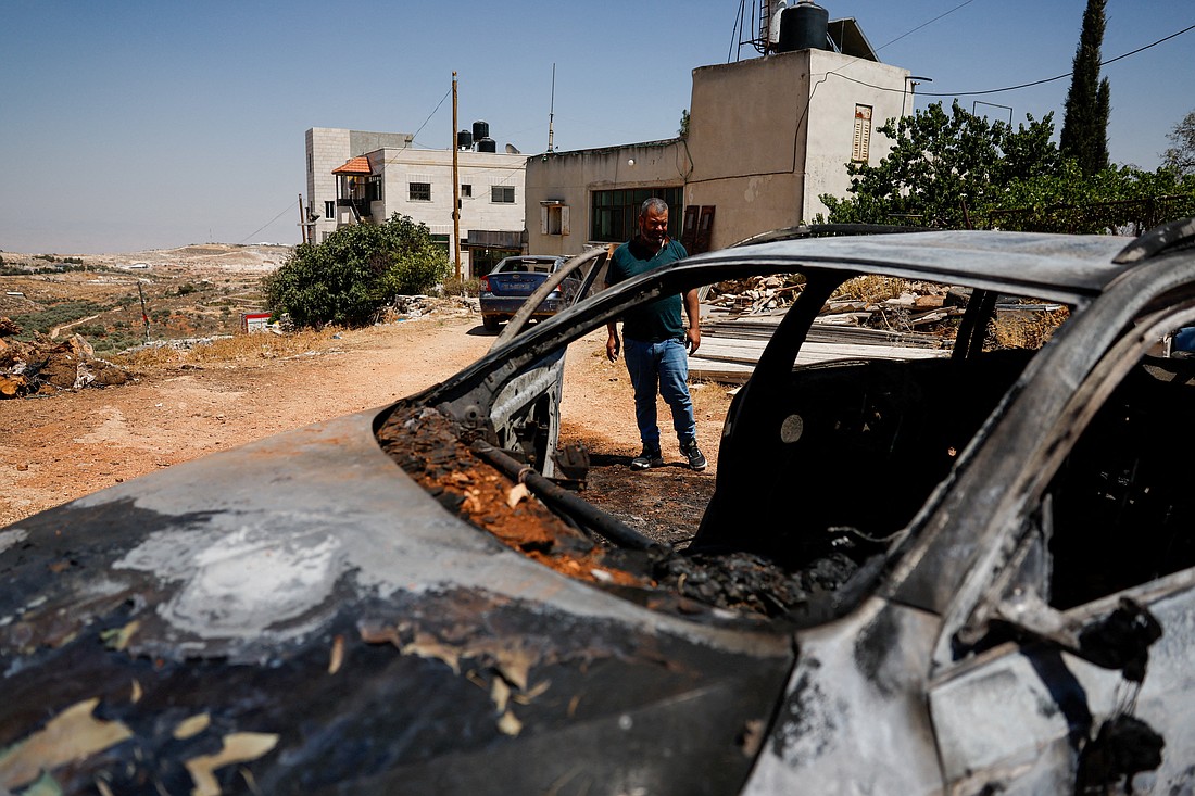 A Palestinian man stands next to a burned car after an attack by Israeli settlers in Kafr Malik, in the Israeli-occupied West Bank, June 26, 2025. (OSV News photo/Ammar Awad, Reuters)