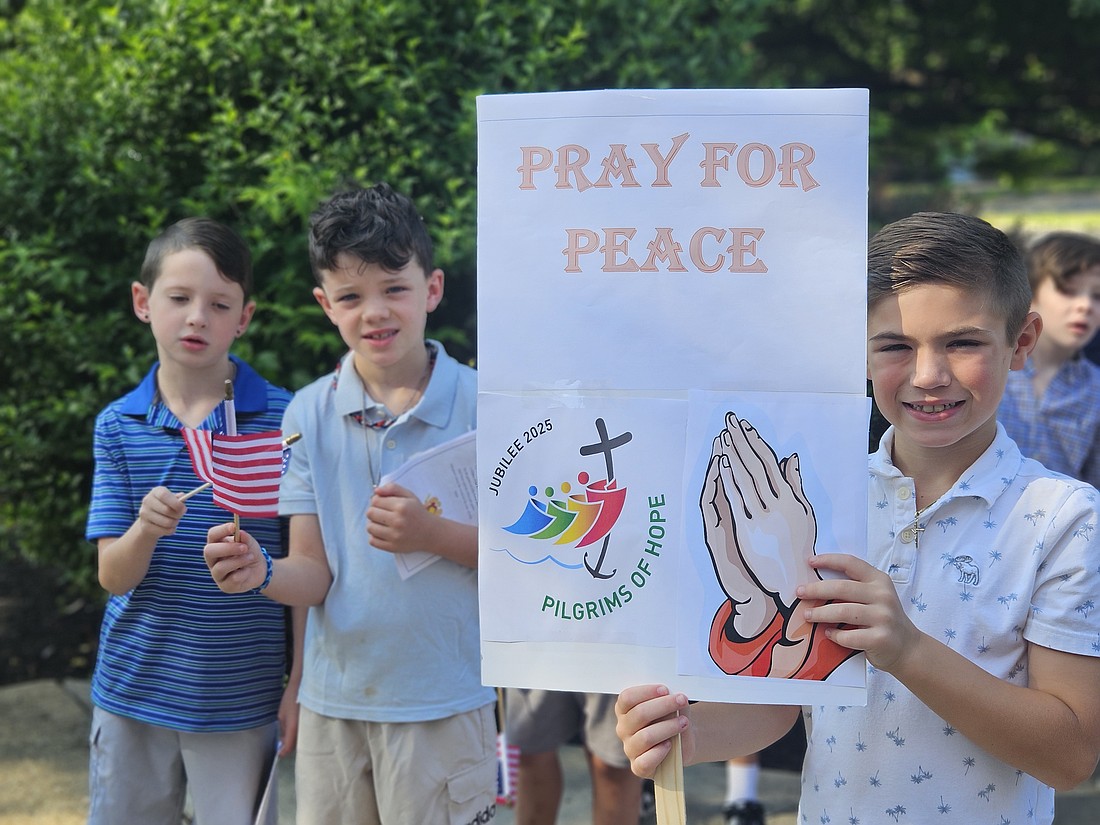 During their July 3 pilgrimage from Our Lady of Sorrows School to the church, some students carried signs with messages reflecting the Jubilee Year of Hope while other students carried American flags. Mary Stadnyk photo