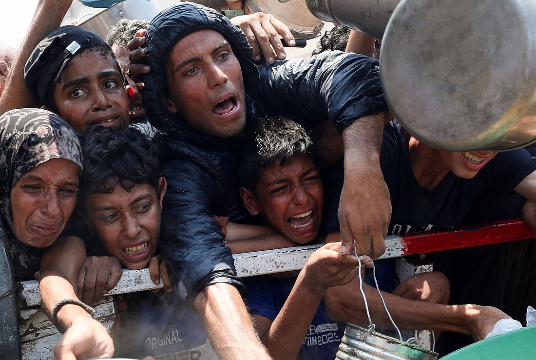 A Palestinian woman and Palestinian children react as they wait to receive food from a charity in Gaza City July 26, 2025, kitchen amid a hunger crisis. A United Nations-affiliated organization that tracks food security worldwide has issued a dire alert confirming that a "worst-case" famine scenario is unfolding across the Gaza Strip. (OSV News photo/Mahmoud Issa, Reuters)