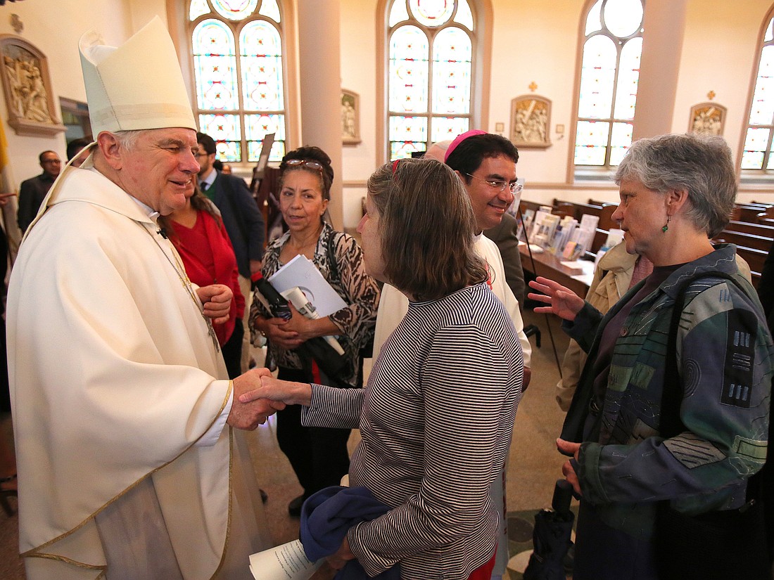 Miami Archbishop Thomas G. Wenski and Bishop Oscar Cantu, then head of the Diocese of Las Cruces, N.M., are pictured in a 2014 file photo greeting people after celebrating a "Mission for Migrants" Mass at St. Peter's Catholic Church on Capitol Hill in Washington. (OSV News photo/Bob Roller0