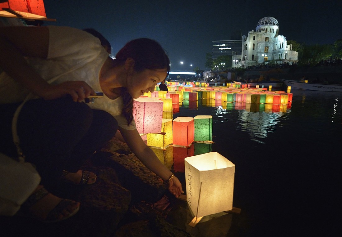 A woman sets a floating candle lantern on the river Aug. 6, 2015, in Hiroshima, Japan, in observance of the 70th anniversary of the atomic bombing of the city. Catholic bishops in Japan are calling for the prohibition of nuclear weapons as they announce a 10-day prayer program marking the anniversary of the Hiroshima and Nagasaki bombings. (CNS photo/Paul Jeffrey)