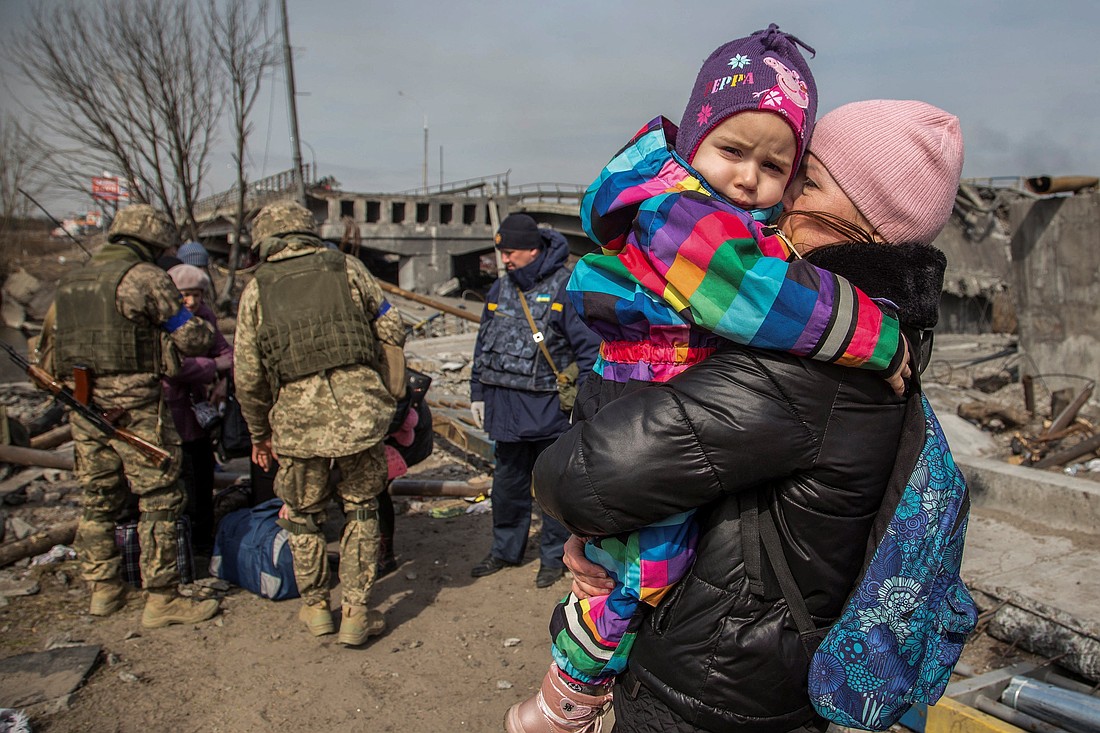 A woman holds a child next to a destroyed bridge during evacuation from Irpin, Ukraine, March 28, 2022, as Russia continues its attack on the country. (OSV News photo/Oleksandr Ratushniak, Reuters)