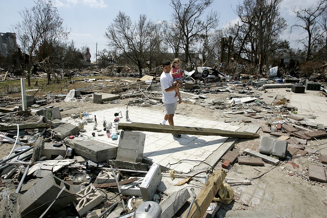 Justin Lopez, and his daughter Olivia, 3, of St. John Parish in Biloxi, Miss., walk through rubble in September 2005 in Biloxi, Miss., after Hurricane Katrina devastated the Gulf Coast community. Aug. 29, 2025, marks the 20th anniversary of the deadly storm, which made landfall in the Gulf Coast region. The powerful storm claimed 1,400 lives, and caused widespread devastation, particularly in New Orleans and along the Mississippi coast. (OSV News photo/Bob Roller)
