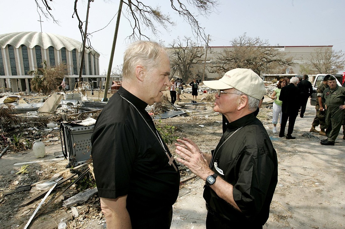 Archbishop Alfred C. Hughes, who was head of the New Orleans Archdiocese at the time, right, talks with Archbishop Paul Cordes, then-the Vatican's top humanitarian aid official, outside St. Michael Church in Biloxi, Miss., Sept. 12, 2005. They were among several officials coordinating relief and reconstruction efforts for parishes and individuals hit hard by Hurricane Katrina. (OSV News photo/Bob Roller)