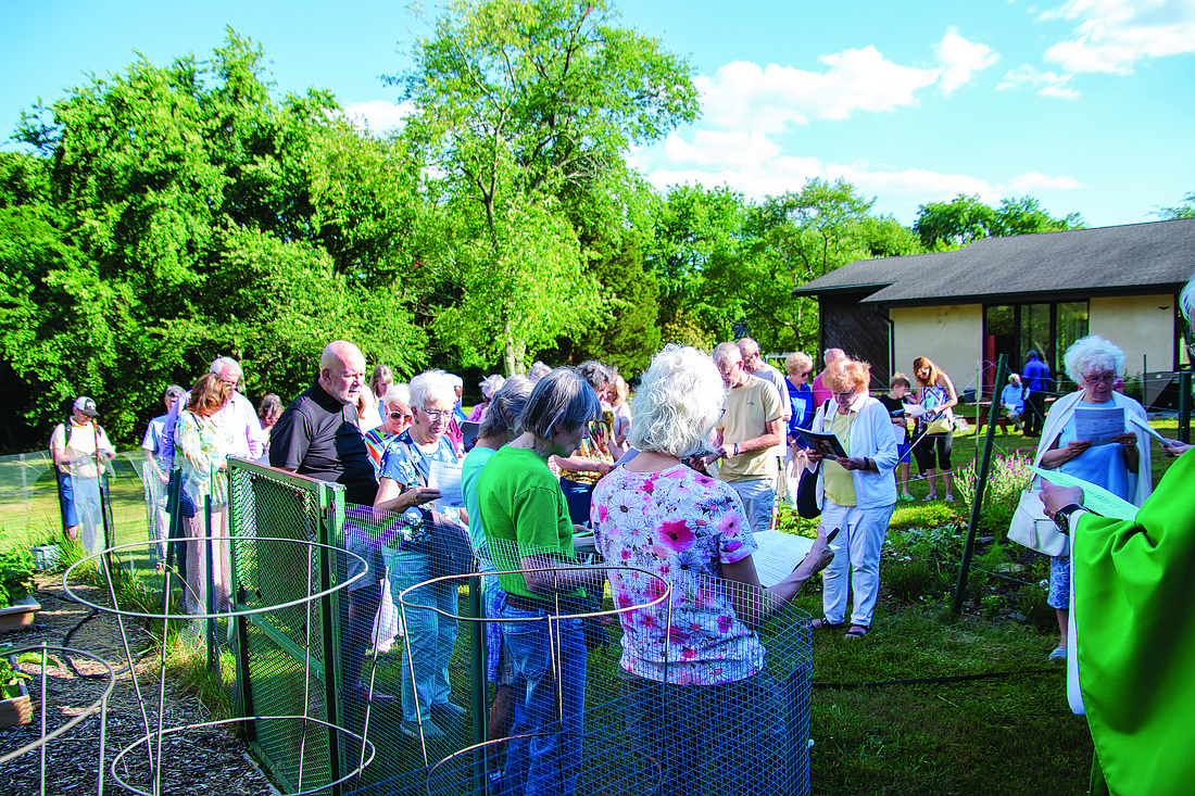 Father Brian T. Butch, partially pictured at right, pastor of St. Anselm Parish, Tinton Falls, leads parishioners in blessing the St. Anselm Community Garden in June 2024. Courtesy photo