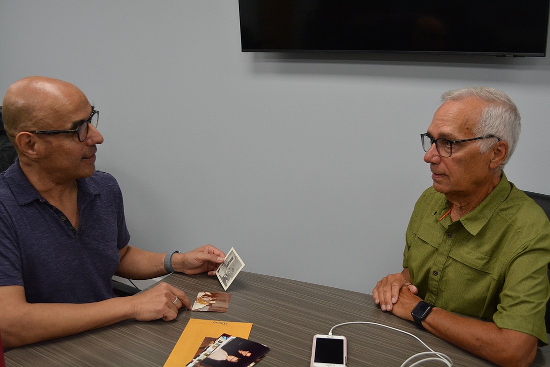 Pope Leo XIV's brother John Prevost, right, and his friend Augustinian Father Ray Flores, look at a photo of what Prevost guessed was the pope's 9th birthday cake and ice cream celebration at home. Chicago suburb of New Lenox, (OSV News photo/Simone Orendain)