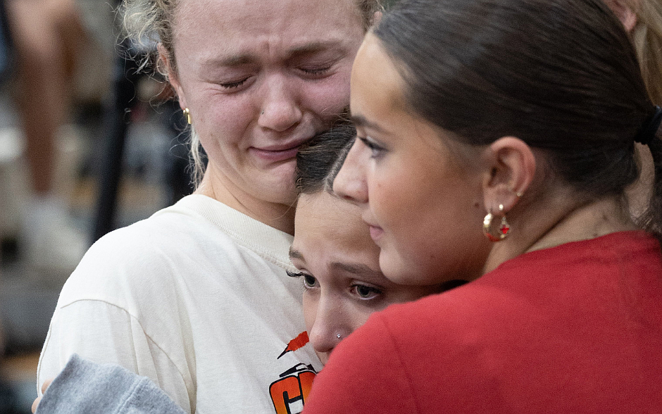 Ellie Mertens, left, youth minister at Annunciation church in Minneapolis, hugs Ella Bradburn (red shirt) and Isabella Manley, who are members of her youth group, during a prayer service at Academy of Holy Angels in Richfield Aug. 27 to support those affected by a shooting at the church that morning. Mertens was inside Annunciation church at the all-school Mass when the shooting occurred. Bradburn and Manley are students at DeLaSalle High School in Minneapolis. (OSV News photo/Dave Hrbacek, The Catholic Spirit)