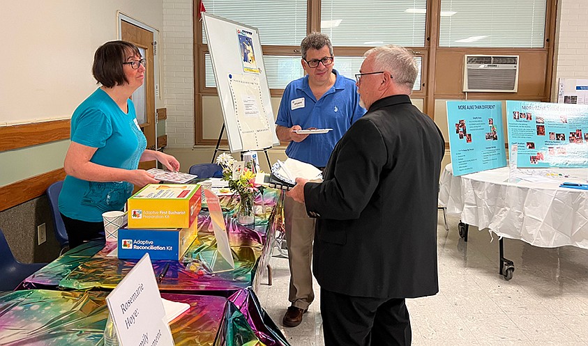 Deacon Stuart Altschuler and his wife, Darlene, discuss workshop details with Father Grogan. All three were spotlight speakers during the conference. Courtesy photo