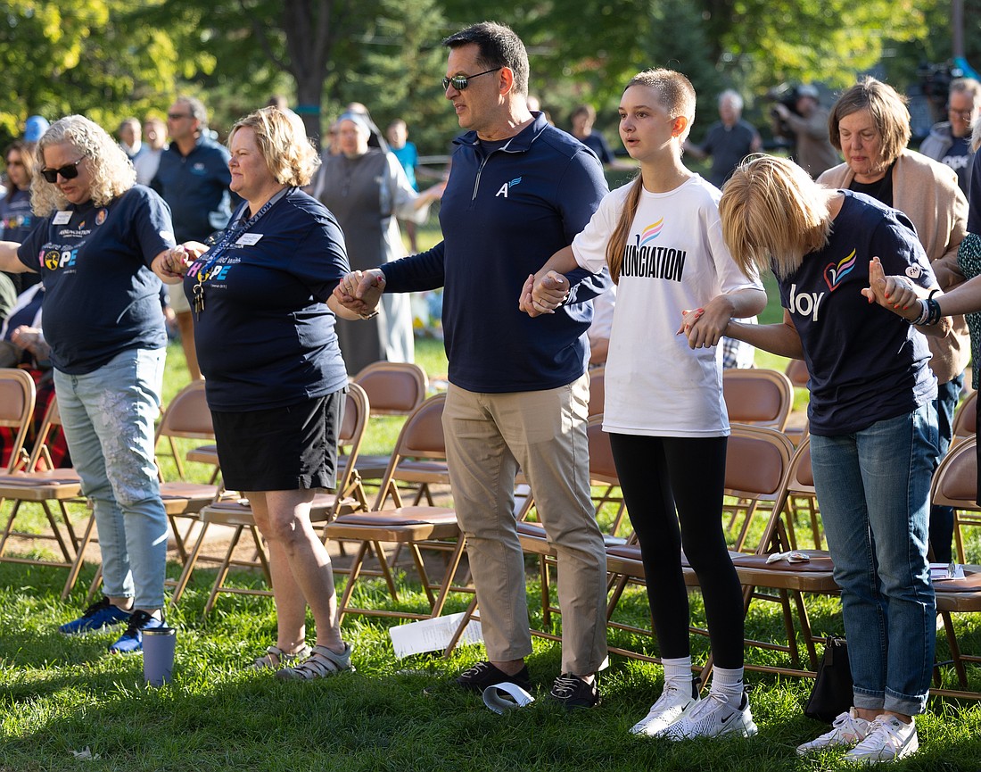 Harry Kaiser, center, prays the Our Father with his daughter, Lydia, second from right, and wife, Leah, right, during a prayer service at Annunciation in Minneapolis, Minn., on Sept. 27, 2025, the one-month anniversary of a shooting at the church. (OSV News photo/David Hrbacek, The Catholic Spirit)