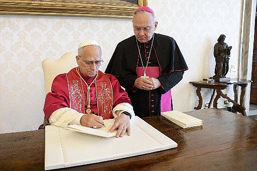 Pope Leo XIV signs his first apostolic exhortation, "Dilexi Te" ("I Have Loved You"), in the library of the Apostolic Palace at the Vatican Oct. 4, 2025, the feast of St. Francis of Assisi, as Archbishop Edgar Peña Parra, the substitute secretary for general affairs at the Vatican Secretariat of State, looks on. The exhortation will be released Oct. 9. (CNS photo/Vatican Media)
