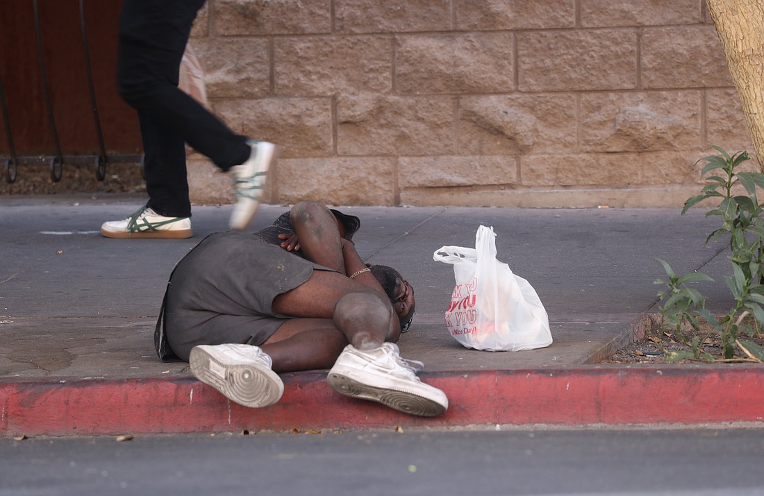 A person walks past a man suffering from homelessness June 25, 2025, along a sidewalk in Phoenix. (OSV News photo/Bob Roller)