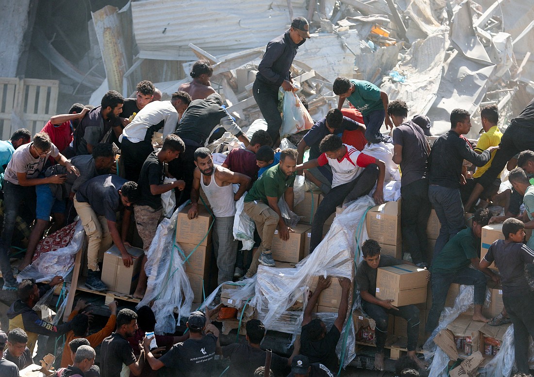 Palestinians collect aid supplies from trucks that entered the Gaza Strip, amid a ceasefire between Israel and Hamas in Gaza City, Oct. 12, 2025. (OSV News photo/Ramadan Abed, Reuters)