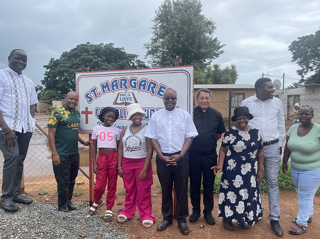 Father Felicien, left, Father Alindogan, and Father Henri, a Nigerian missionary priest, center, are shown with people from Pretoria.