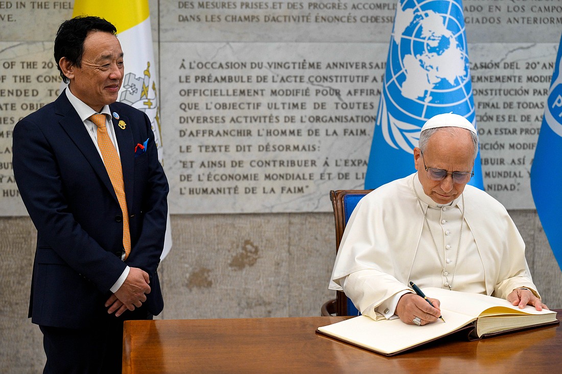 Pope Leo XIV signs the guest book as Qu Dongyu, director-general of the U.N. Food and Agriculture Organization, looks on during the pope's visit to FAO headquarters in Rome Oct. 16, 2025, for the celebration of the agency’s 80th anniversary and World Food Day. (CNS photo/Vatican Media)