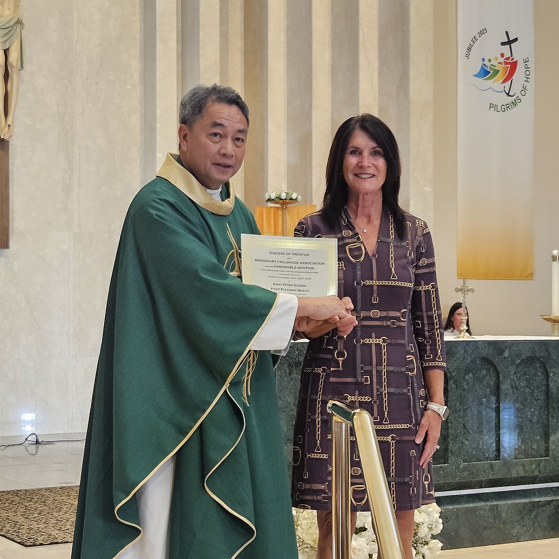 Father Alindogan, diocesan missions director, presents a certificate to Debra Ostrowski, principal of St. Peter School, Point Pleasant Beach, which was among the schools and parish religious education programs in the Diocese honored for highest contributions to the missions for 2024-2025. Mary Stadnyk photo