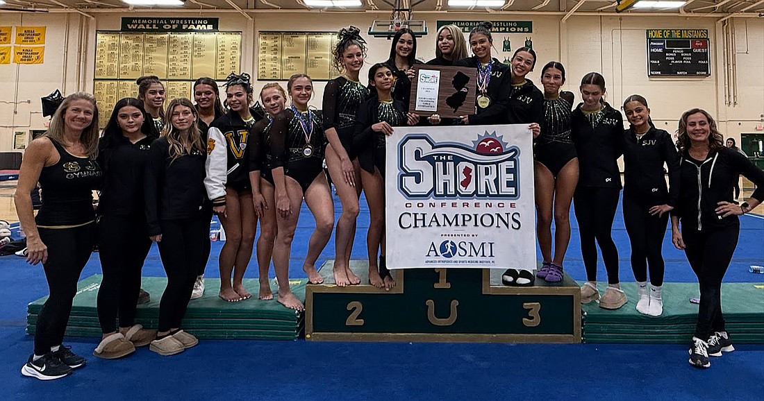 The St. John Vianney gymnastics team proudly show off their third Shore Conference Tournament banner in five years and fifth overall after winning the title Oct. 25. Courtesy photo