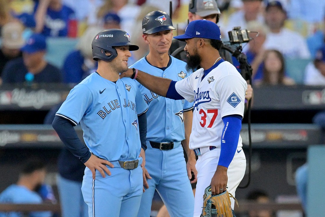 Los Angeles Dodgers right fielder Teoscar Hernandez (37) and Toronto Blue Jays center fielder Daulton Varsho (5) talk as first base coach Mark Budzinski (53) looks on during a challenge on a play in the first inning during game five of the 2025 MLB World Series at Dodger Stadium in Los Angeles Oct. 29, 2025. A devout Catholic, Budzinski, 42, has long said that his relationship with God sustains him through every inning – from the joy of victory to the pain of loss. Mandatory Credit: (OSV News photo/Jayne Kamin-Oncea-Imagn Images via Reuters)