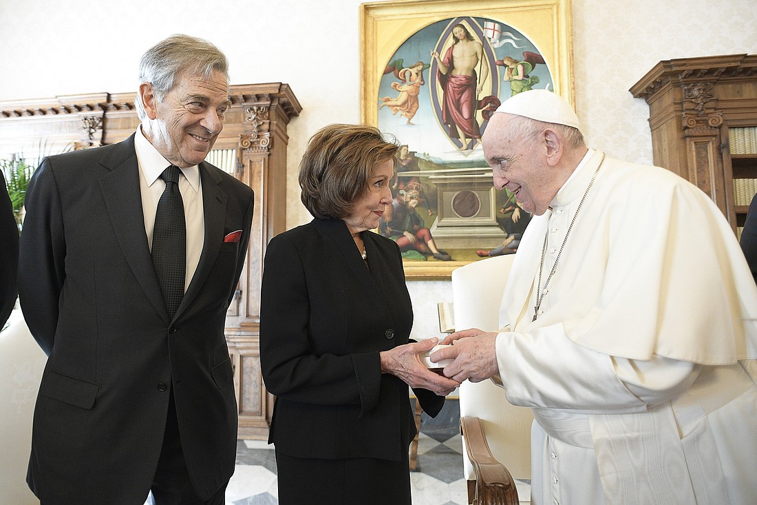 Pope Francis presents a gift to U.S. House Speaker Nancy Pelosi, D-Calif., accompanied by her husband, Paul, during a private audience at the Vatican Oct. 9, 2021. (CNS photo/Vatican Media)