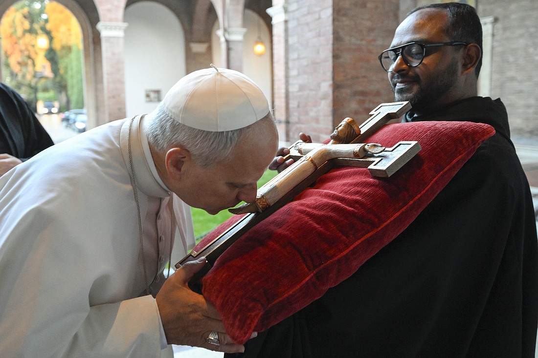 Pope Leo XIV kisses a crucifix as he enters Rome's Church of St. Anselm Nov. 11, 2025, the 125th anniversary of the church's dedication. (CNS photo/Vatican Media)