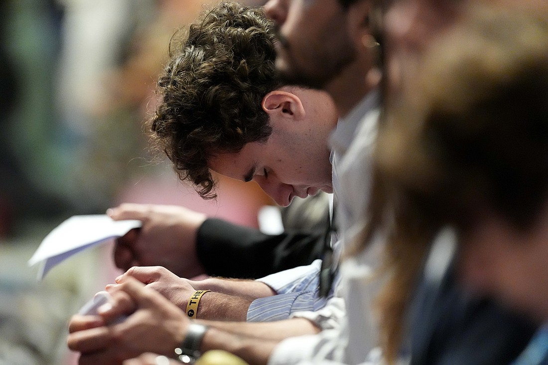 A young man bows his head in prayer during Holy Thursday’s Mass of the Lord’s Supper at the Altar of the Chair in St. Peter’s Basilica at the Vatican April 17, 2025. (CNS photo/Lola Gomez)