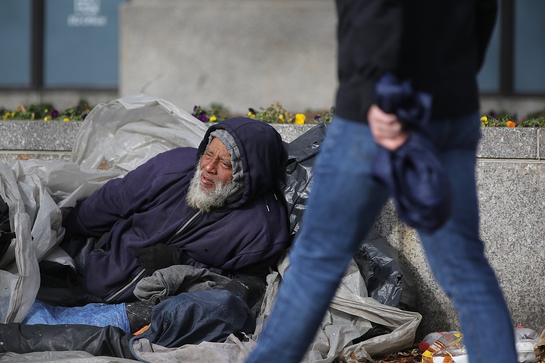 A person passes a homeless man lying on a street in Washington Jan. 28, 2023. (OSV News photo/Bob Roller)