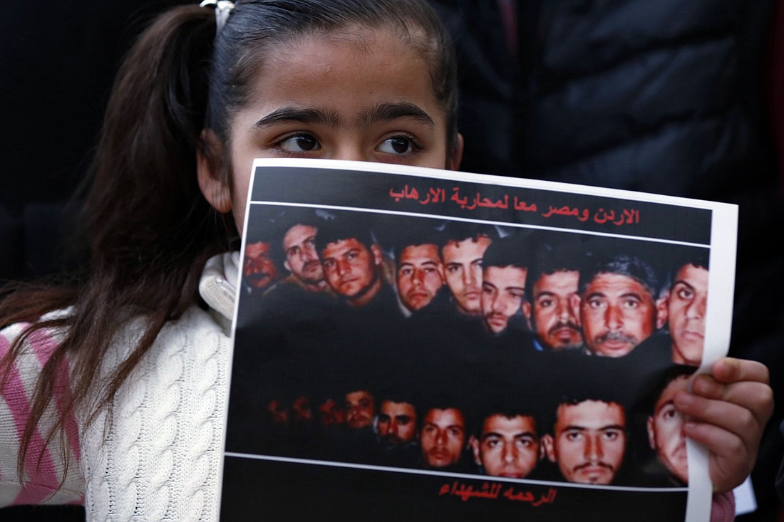 A girl holds up a poster with pictures of the 21 Egyptian Coptic Christians beheaded by the Islamic State group in Libya, during a show of solidarity in front of the Egyptian embassy in Amman, Jordan, in this Feb. 17, 2015, file photo. (OSV News photo/Muhammad Hamed, Reuters)