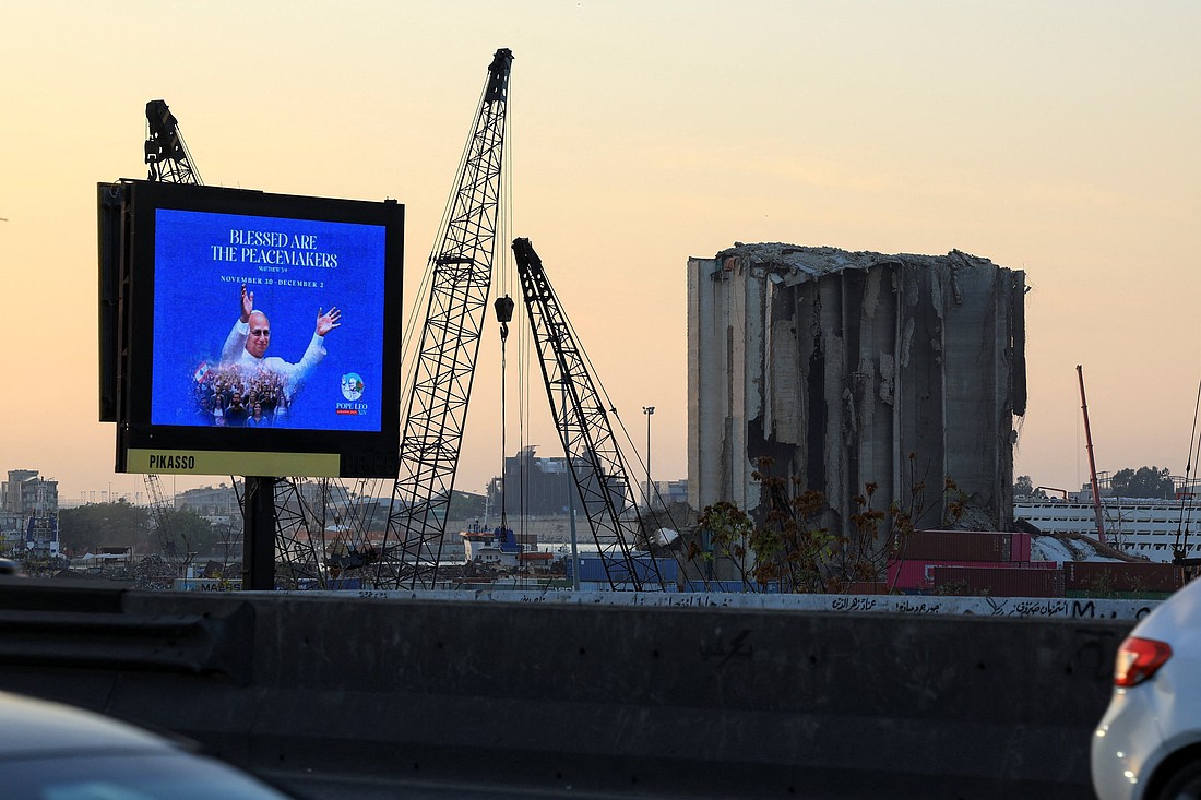 A digital billboard showing Pope Leo XIV stands along a road in Beirut Nov. 19, 2025,  ahead of his planned visit to Lebanon. Nearby are partially collapsed grain silos that were damaged in the Aug. 4, 2020, Beirut port blast. (OSV News photo/Mohamed Azakir, Reuters)