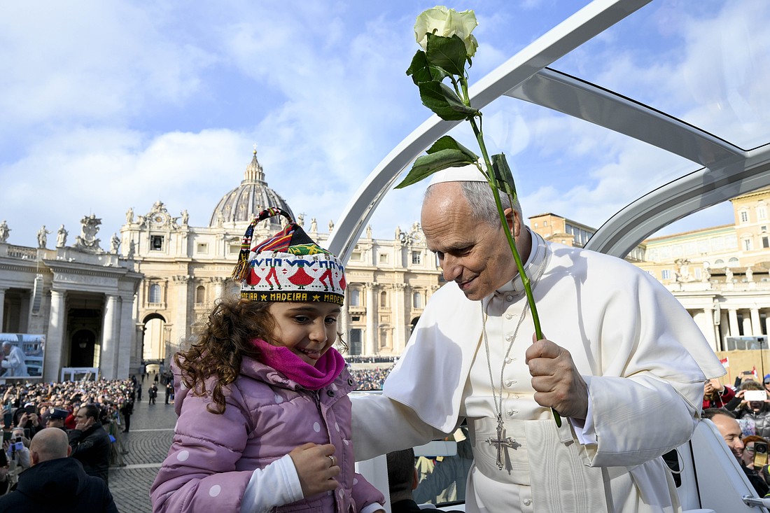 Pope Leo XIV receives a white rose from a child as he rides around St. Peter's Square at the Vatican before his weekly general audience Nov. 26, 2025. (CNS photo/Vatican Media)