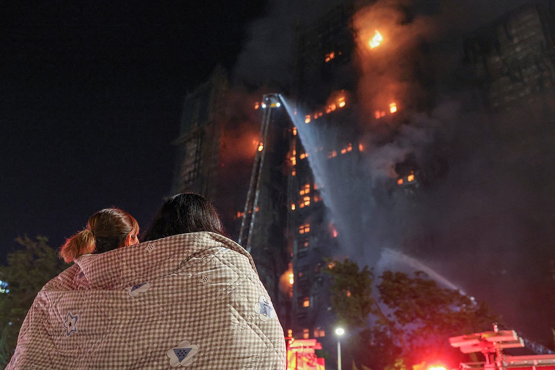 Residents wrapped in blankets watch flames engulf bamboo scaffolding at Wang Fuk Court apartment complex after a major fire broke out in the Tai Po district of Hong Kong Nov. 26, 2025. Hong Kong leader John Lee said that 36 people were reported killed in the fire that spread through a dense high-rise residential housing complex, and that another 279 people were reported missing. (OSV News photo/Tyrone Siu, Reuters)
