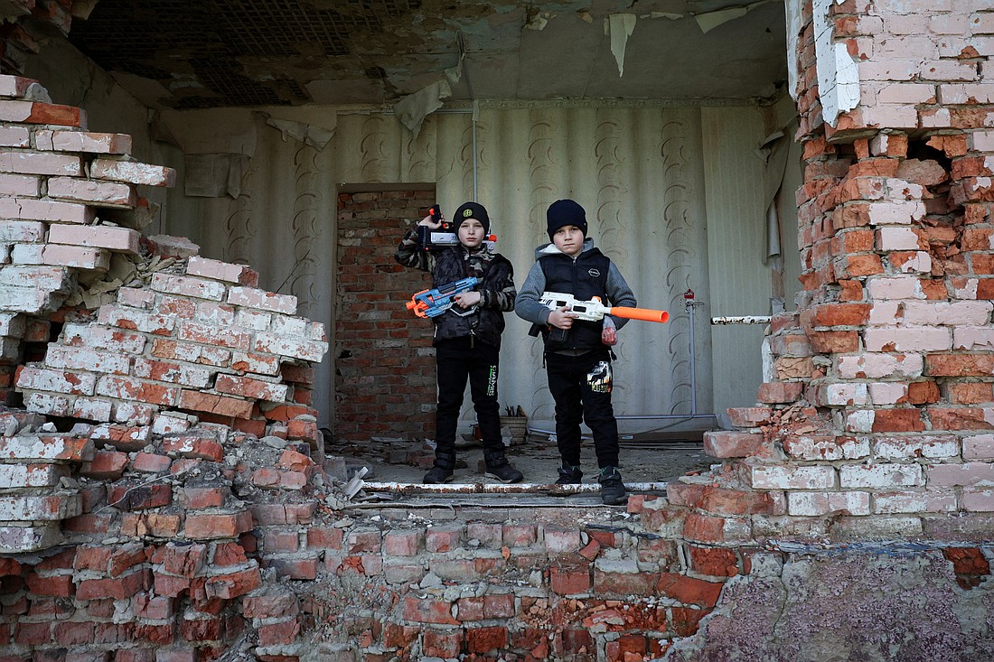 Siblings Andrii, 8, and Maksym Tupkalenko, 6, two of the last children left in their frontline village of Kalynove, Ukraine, pose for a photo with toy guns inside a damaged building April 11, 2025. (OSV News photo Violeta Santos Moura, Reuters)