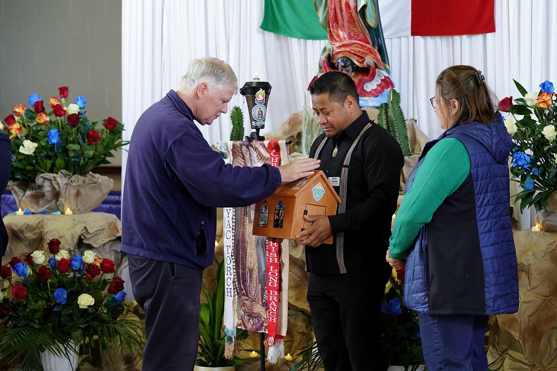 Father John K. Butler, pastor, St. Michael Parish, Long Branch, blesses the petitions as the Tepeyac Torch arrives at Mother of Mercy Parish, Asbury Park Nov. 16. The torch had been hosted by St. Michael Parish the previous week.
