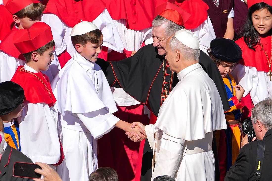 Pope Leo XIV greets fourth grader Augie Wilk, who was elected "Pope Augustine" in a mock conclave at Our Lady of Mount Carmel Academy in Chicago, during the pope’s weekly general audience in St. Peter's Square at the Vatican Oct. 8, 2025. Cardinal Blase J. Cupich of Chicago looks on. The students’ reenactment May 6 of a papal election went viral days before Pope Leo’s own election May 8. (CNS photo/Lola Gomez)