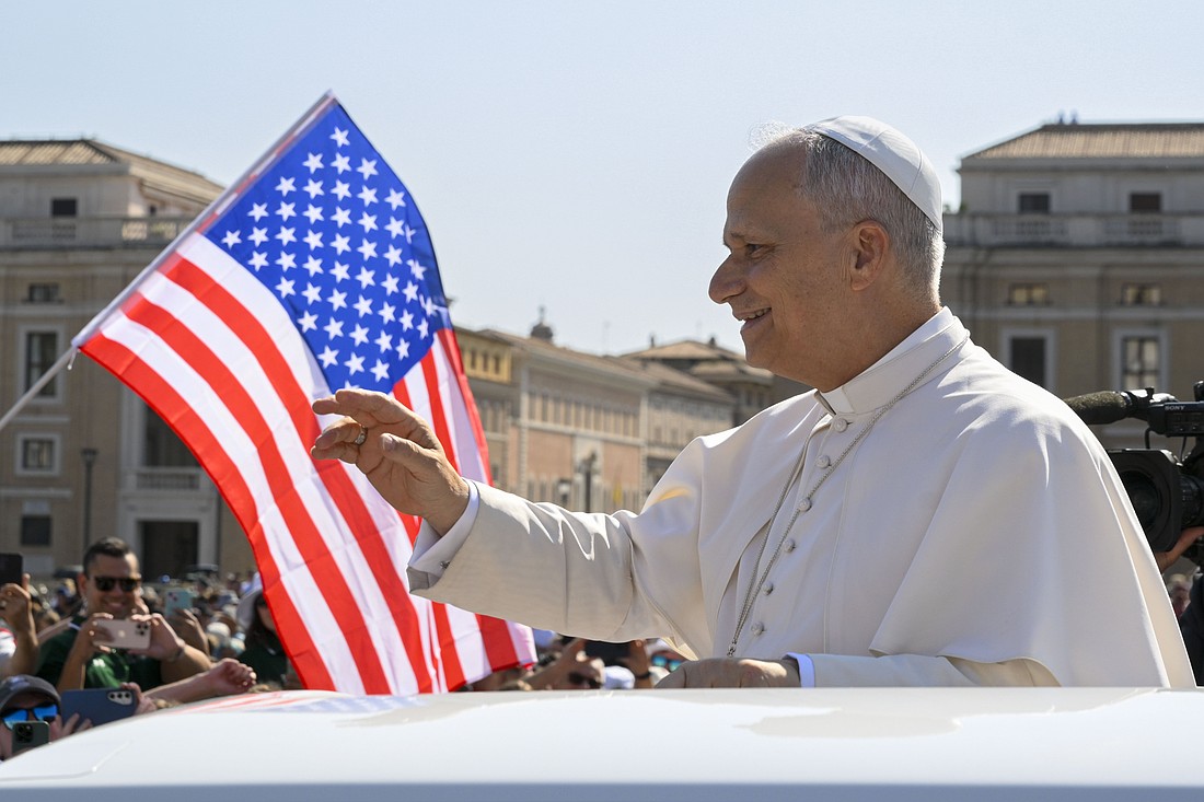 With a U.S. flag in the background, Pope Leo XIV waves to the crowd from the popemobile as he rides around St. Peter's Square at the Vatican before his weekly general audience Aug. 6, 2025. (CNS photo/Vatican Media)
