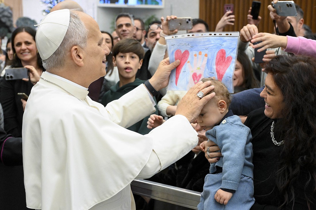 Pope Leo XIV receives a drawing after his after his annual pre-Christmas meeting with Vatican employees and their families in the Paul VI Audience Hall at the Vatican Dec. 22, 2025. (CNS photo/Vatican Media)