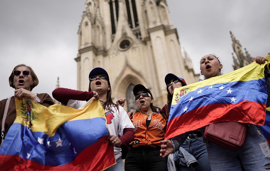 Varias personas ondean banderas venezolanas mientras participan de una manifestación frente a la Basílica Menor de Nuestra Señora de Lourdes en Bogotá el 4 de enero de 2026, pidiendo una transición democrática, tras los ataques lanzados por Estados Unidos contra Venezuela, que resultaron en la captura del presidente Nicolás Maduro y su esposa, Cilia Flores. (Foto OSV News/Sergio Acero, Reuters)..
